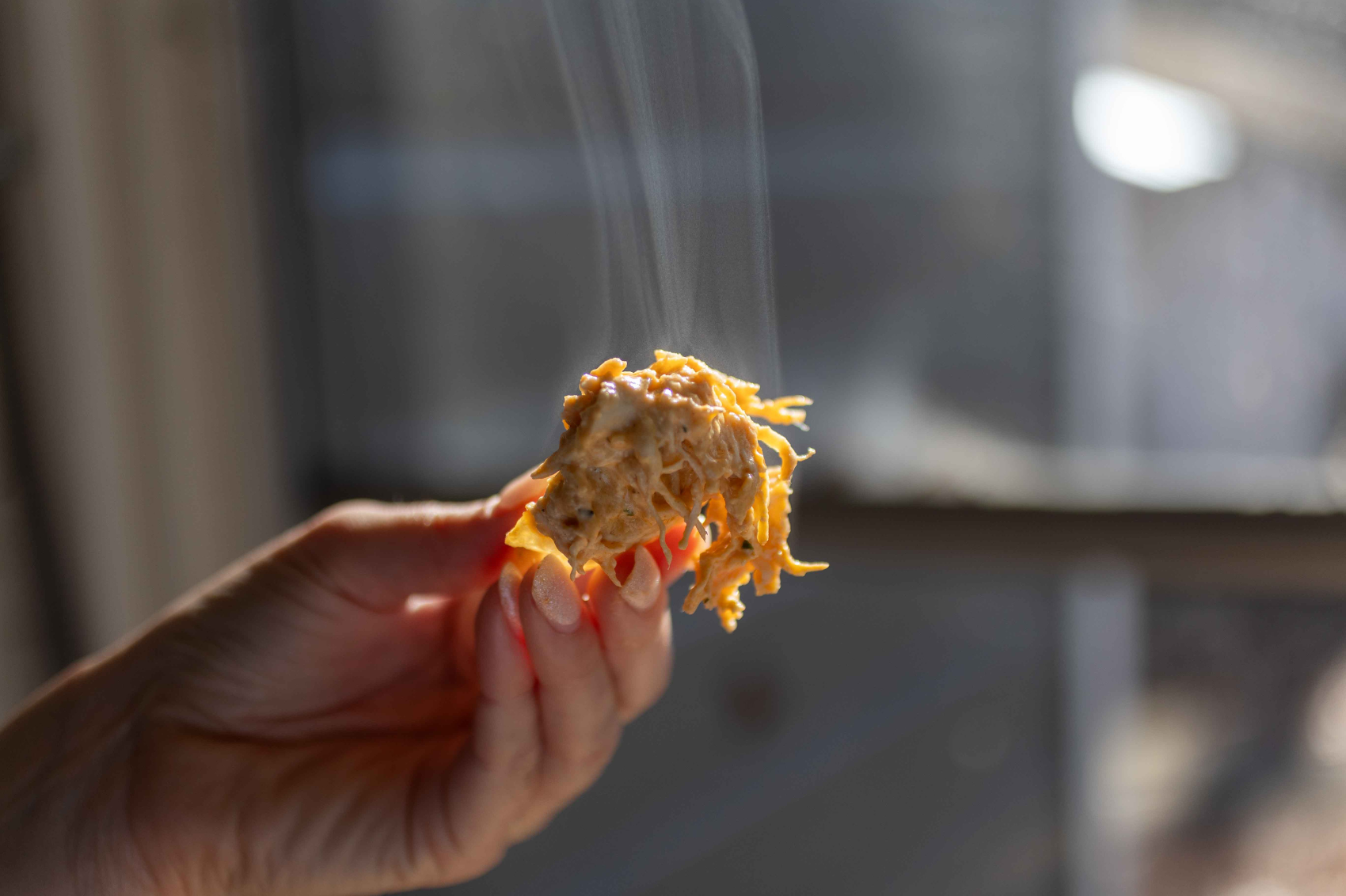Buffalo Chicken Dip being held up by a hand. 