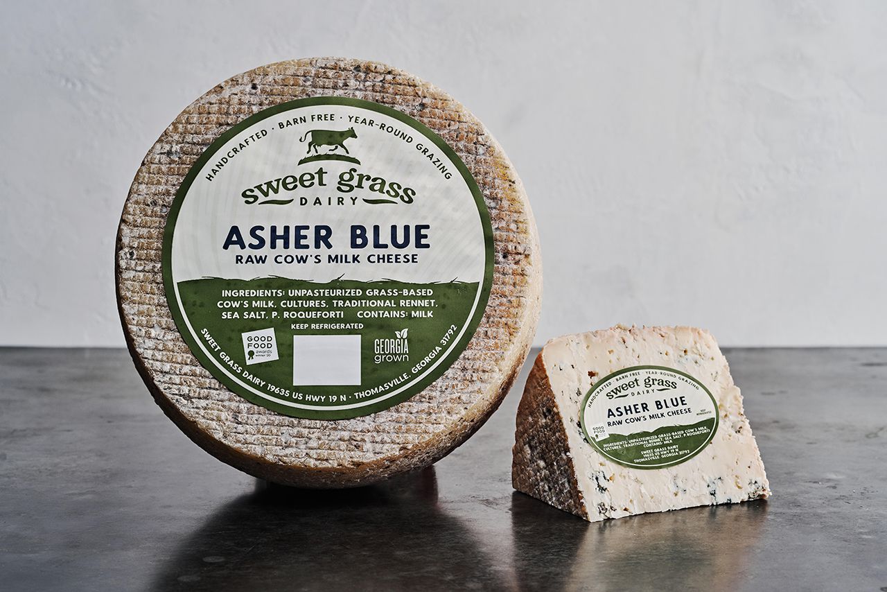 Sweet Grass Dairy's Asher Blue positioned to show the packaging and logo of the cheese. 