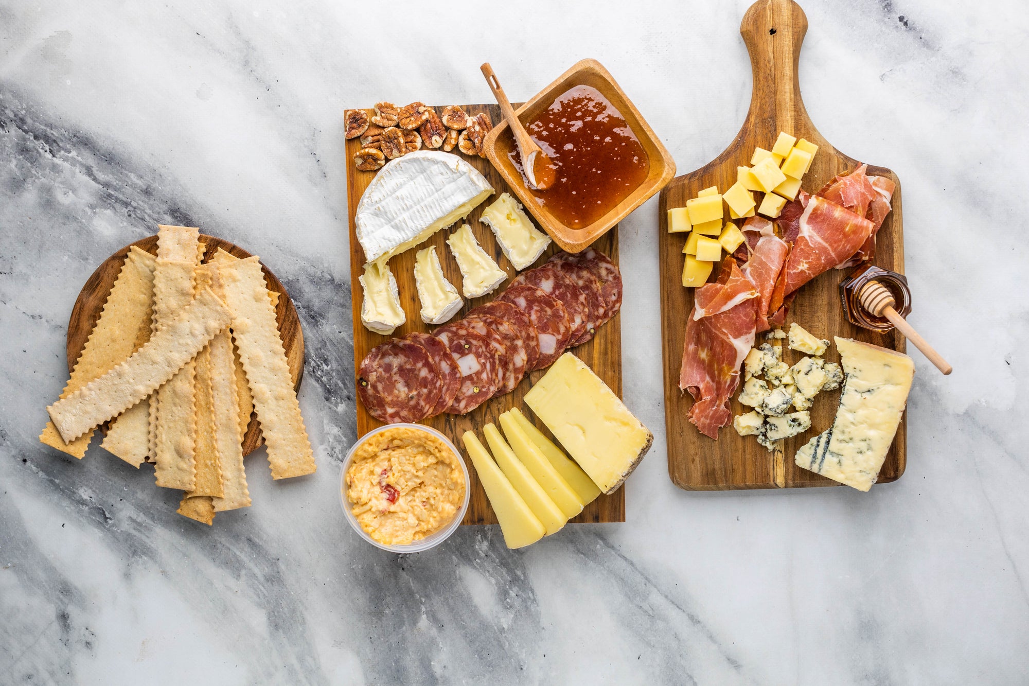 Cheese, Jam, Proscuitto, Honey, Pecans, Crackers on a cheese board. 
