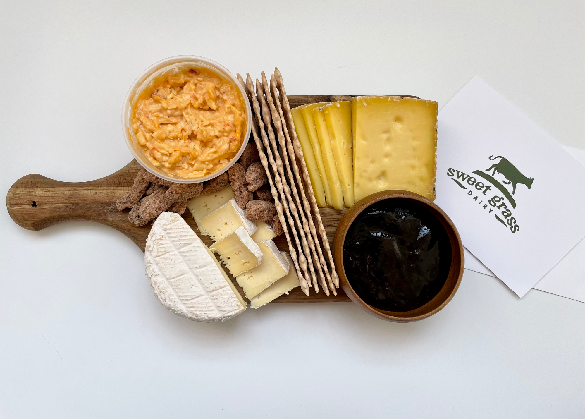 Cheese, crackers, jam, and pecan on a cheese board. 